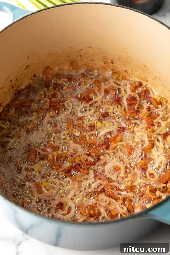Golden Katsu Ramen 6 Bacon and shallots cooking in a pot.