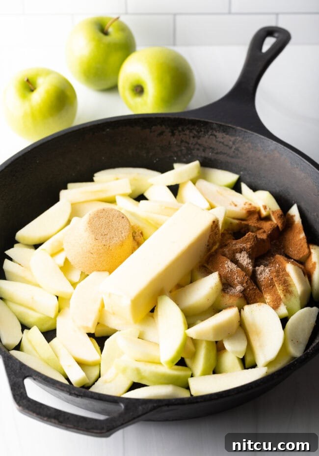 Gooey Caramel Apple Bake 6 Freshly sliced Granny Smith apples, a stick of unsalted butter, rich brown sugar, and aromatic spices ready in a cast iron skillet for the apple filling.