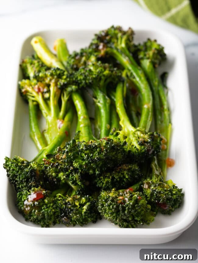 Roasted Broccolini with Chili Honey Glaze 2 Roasted broccolini with sweet chili glaze stacked on a white rectangle serving platter.