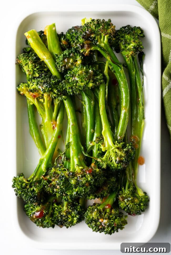 Roasted Broccolini with Chili Honey Glaze 3 Top down oven roasted broccolini recipe with sweet chili glaze stacked on a white rectangle serving platter.
