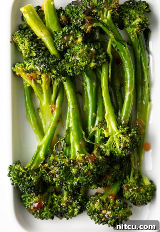 Roasted Broccolini with Chili Honey Glaze 8 Roasted broccolini recipe finished - with sweet chili glaze stacked on a white rectangle serving platter.
