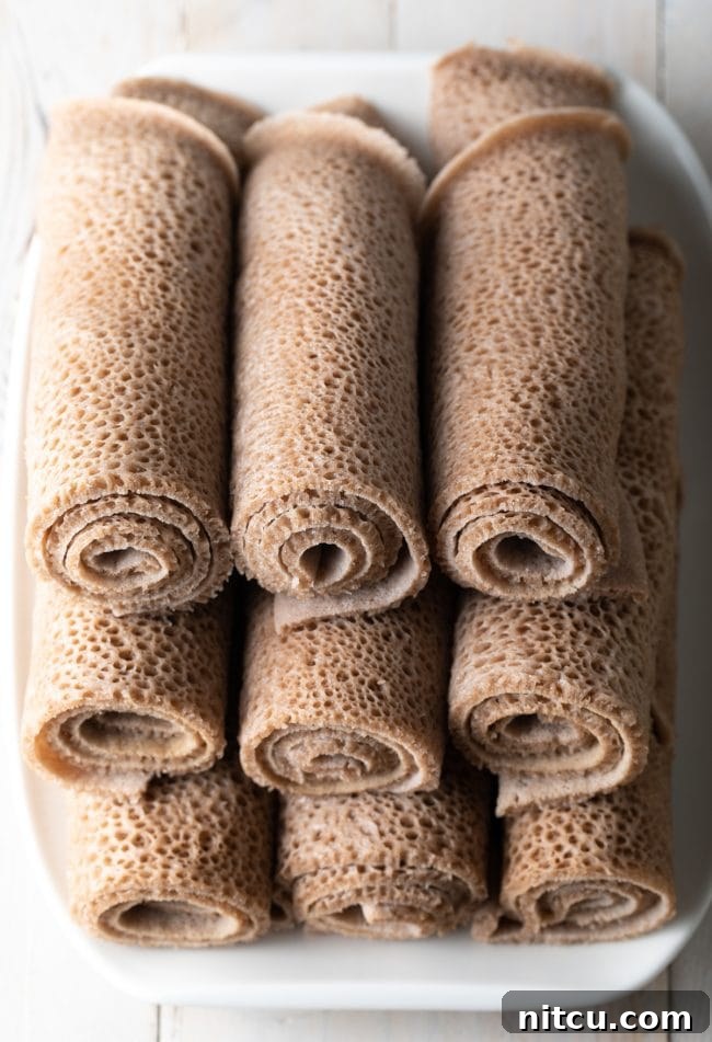 Ethiopian Injera bread rolled and stacked on a white platter. 