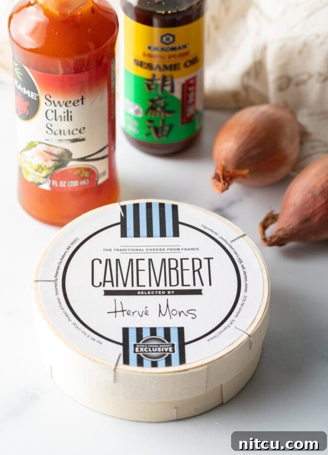 Gooey Baked Camembert Delight 5 Ingredients you need: wheel of cheese, bottle of sweet chili sauce, sesame oil, and whole shallots.