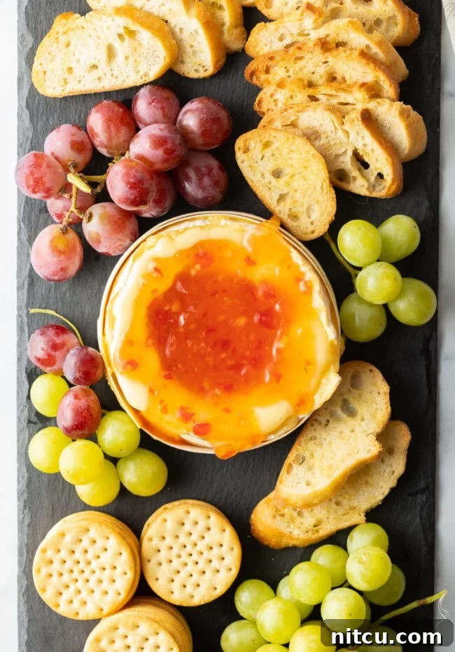 Gooey Baked Camembert Delight 10 Top down view, sweet chili sauce added to the baked cheese surrounded by dippers.