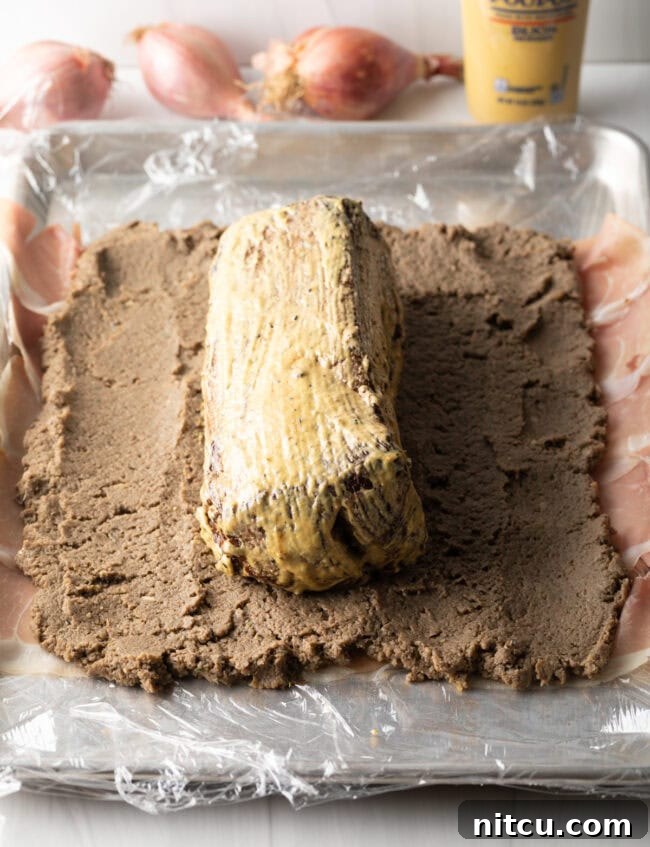 Mustard coated tenderloin placed in the center of the mushroom pate.