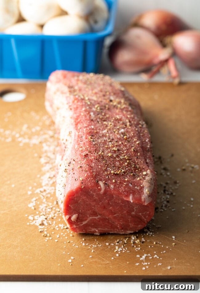 Raw beef tenderloin coated with salt and pepper.