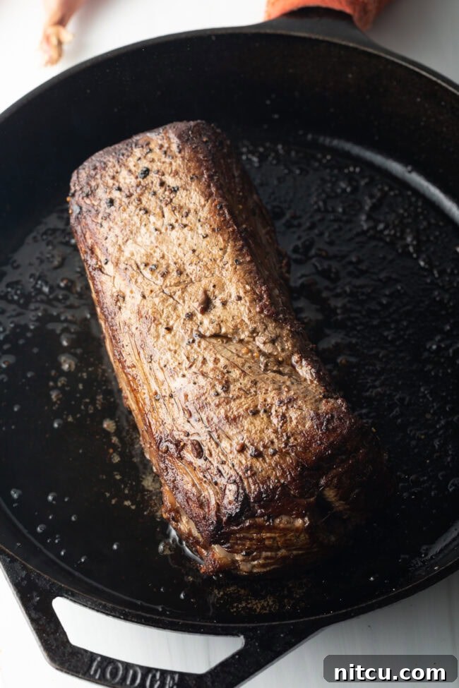 Searing beef tenderloin in a cast iron skillet.