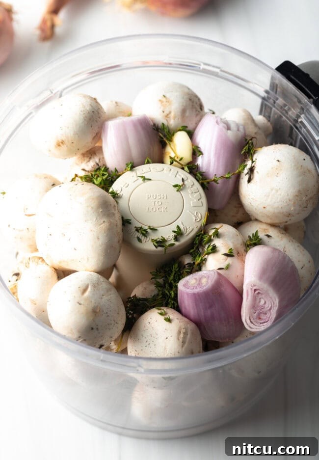 Food processor with mushrooms, herbs, and shallots.