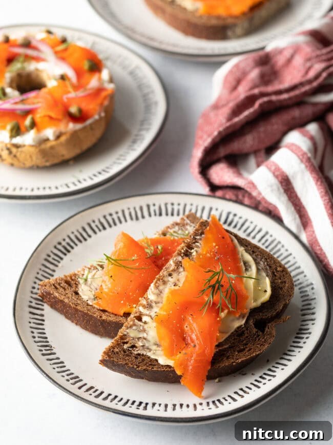 Homemade Gravlax Cured Salmon 2 Two slices of pumpernickel bread with butter and pieces of gravlax on top, garnished with fresh dill.