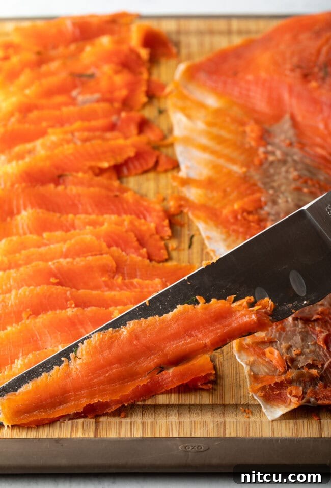Homemade Gravlax Cured Salmon 11 Closeup of a sharp knife expertly cutting thin slices of cured gravlax against the grain.