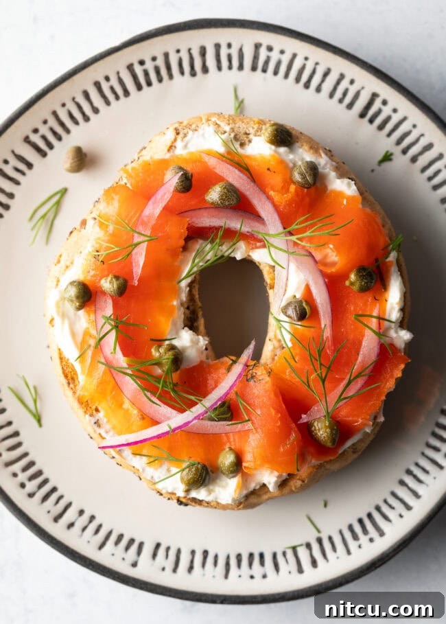Homemade Gravlax Cured Salmon 12 Top down view half of a bagel with cream cheese, smoked gravlax, capers and sliced red onions, a quintessential breakfast.