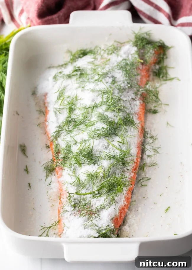 Homemade Gravlax Cured Salmon 7 Salmon fillet in a baking dish covered in curing ingredients, ready for the pressing stage.