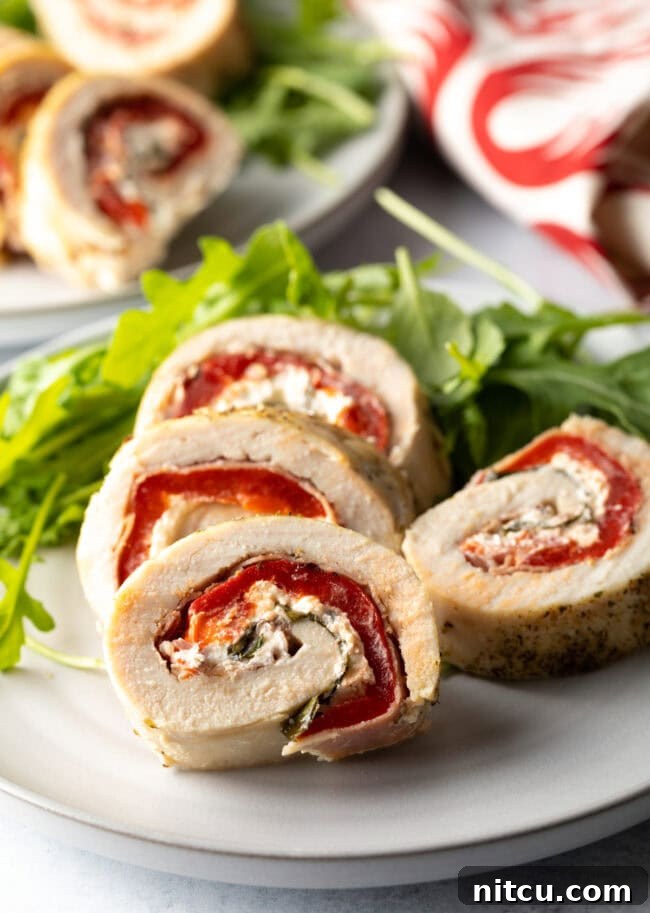 Savory Stuffed Chicken Rolls 13 Plated chicken roulade slices with fresh herbs, ready to be served.