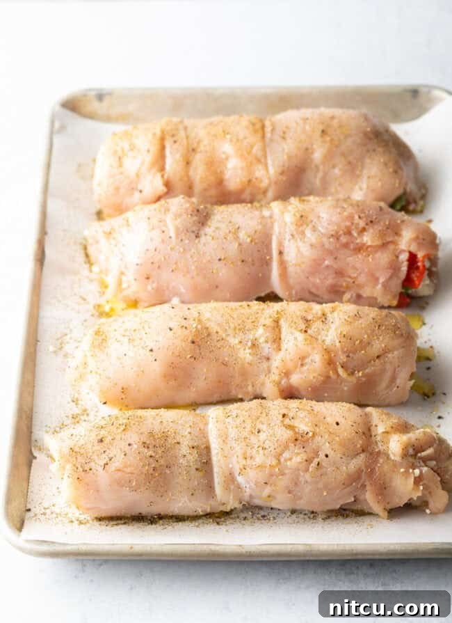 Savory Stuffed Chicken Rolls 10 Four stuffed and rolled chicken breasts on a baking tray. They have been seasoned with olive oil and Italian seasonings, ready for the oven.