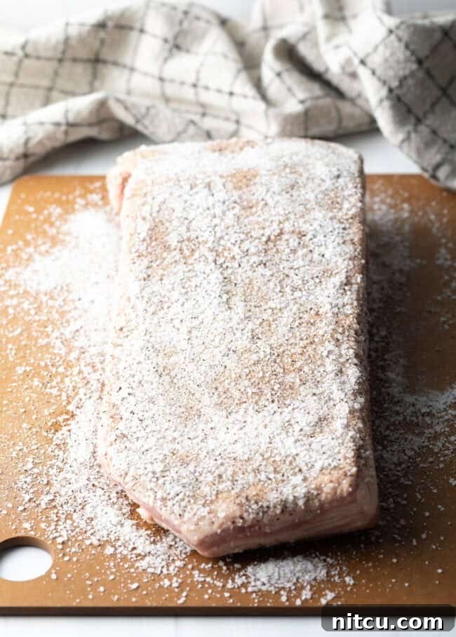 Perfect Homemade Beef Bacon 5 Slab of meat on a cutting board, coated with salt seasoning.