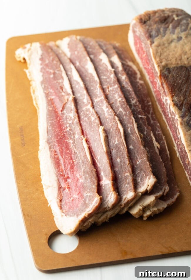 Perfect Homemade Beef Bacon 8 Slab of cured beef bacon cut into 6 thick slices on a cutting board.