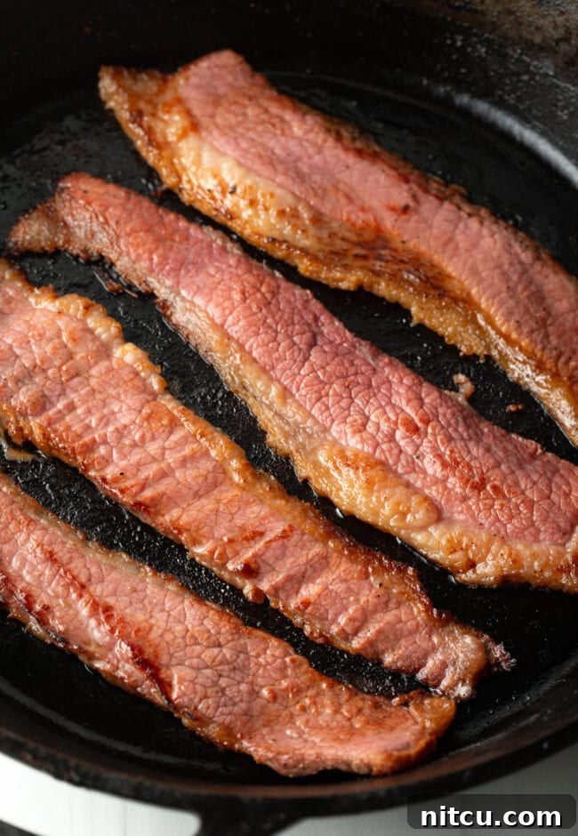 Perfect Homemade Beef Bacon 10 Close view of bacon cooking in a skillet.