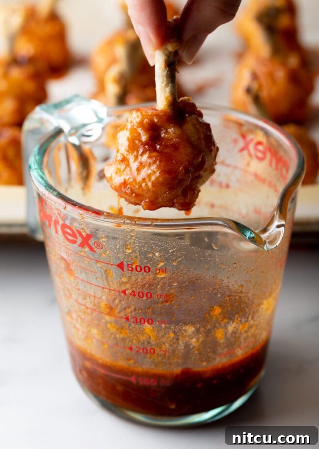 Irresistible Sweet Heat Chicken Lollipops 13 Hand dipping baked drummie into the sauce.