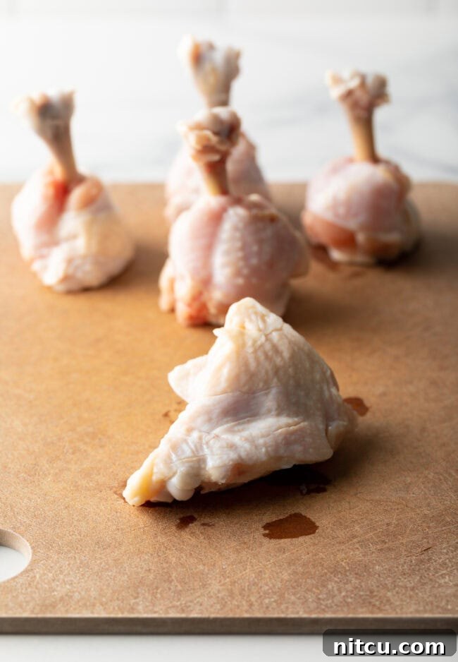 Irresistible Sweet Heat Chicken Lollipops 6 Raw drumettes on a cutting board.