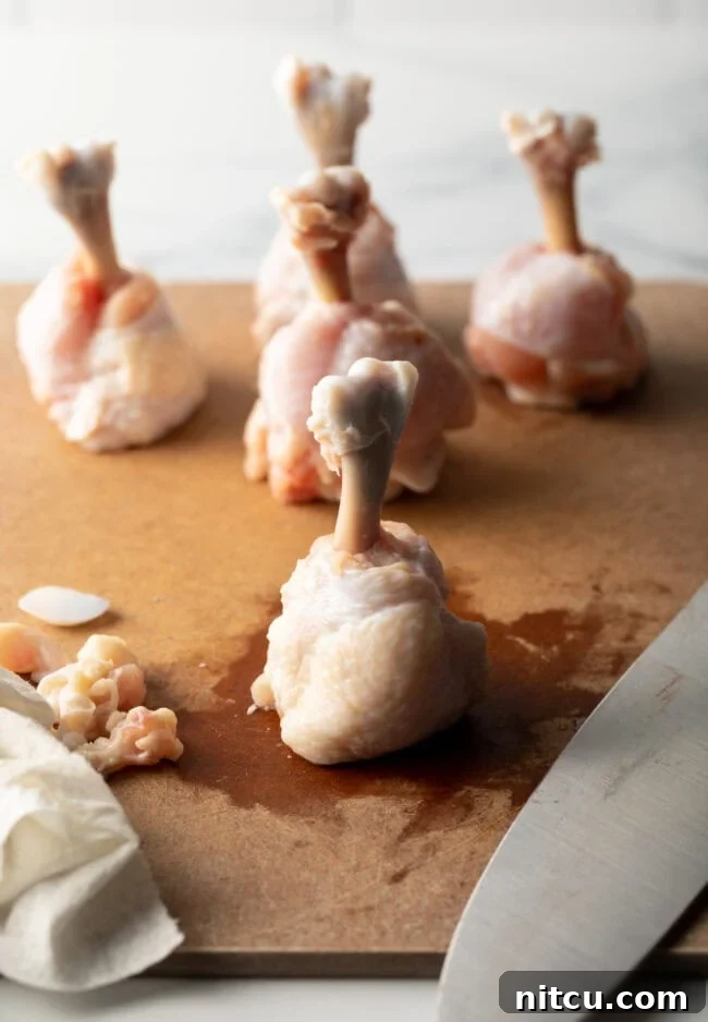 Irresistible Sweet Heat Chicken Lollipops 9 Raw drumette sitting top down on a cutting board.