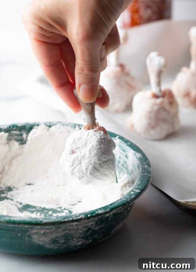 Irresistible Sweet Heat Chicken Lollipops 10 Hand dipping frenched chicken drumette into cornstarch mixture.