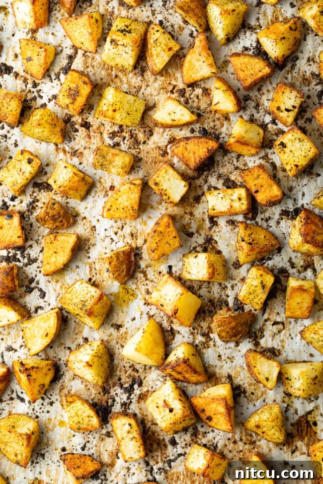 Russet Potatoes Ultimate Recipe and Cooking Tips 8 Top down view cubes of roasted russet potatoes on a baking sheet lined with parchment.