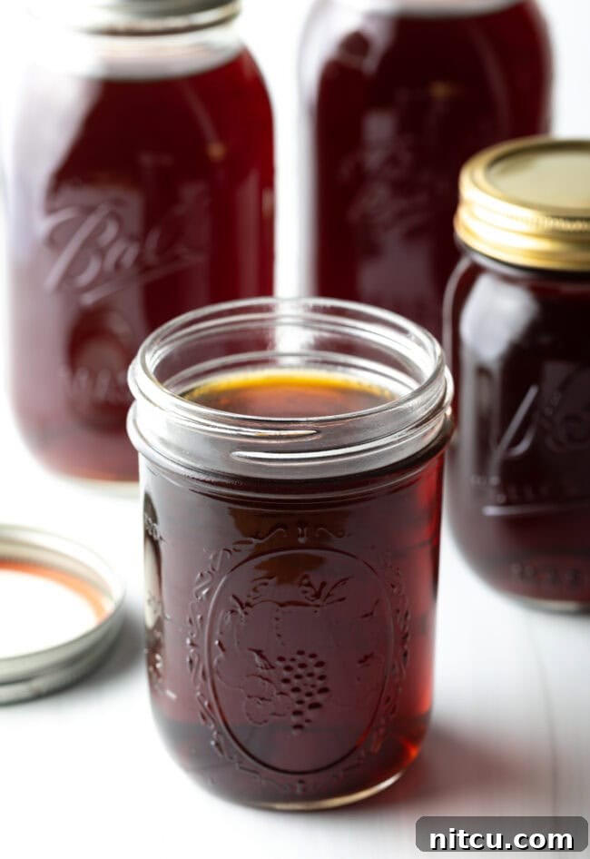Golden Beef Essence 12 A glass jar filled with beef consomme with more jars in the background.