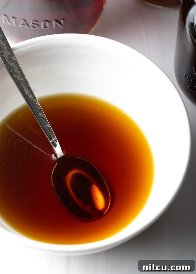 Golden Beef Essence 14 Metal spoon in a white bowl with homemade beef consommé.