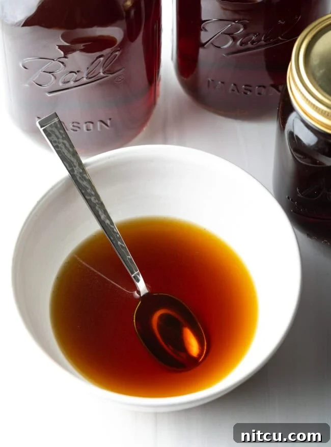 Golden Beef Essence 3 Top down view of clarified beef broth in a white bowl with a spoon.