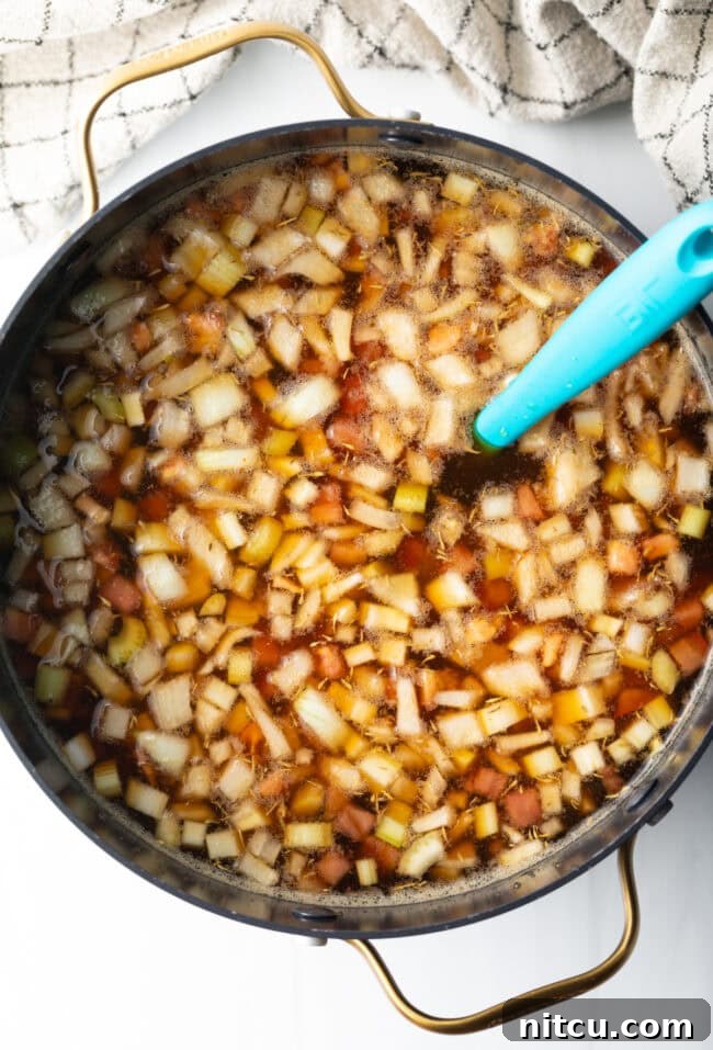 Golden Beef Essence 8 Top down view of consomme ingredients boiling in a pot.
