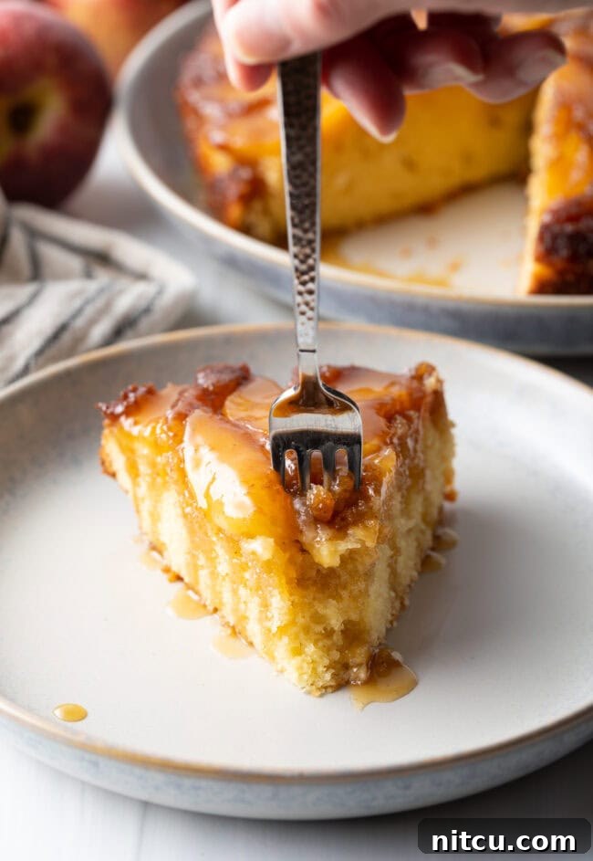 Effortless Apple Caramel Flip Cake 11 Fork taking a bite from slice of apple upside down cake on a white plate.