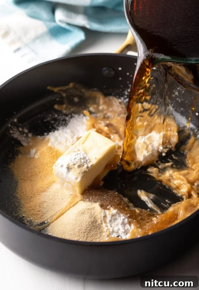 Adding beef stock to the cooking pan with the butter, cornstarch, and spices, while whisking.