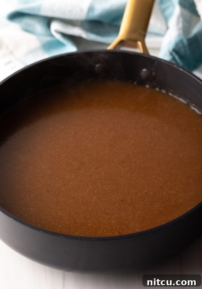 Homemade brown beef gravy bubbling gently in a deep black skillet, showing its thickened consistency.