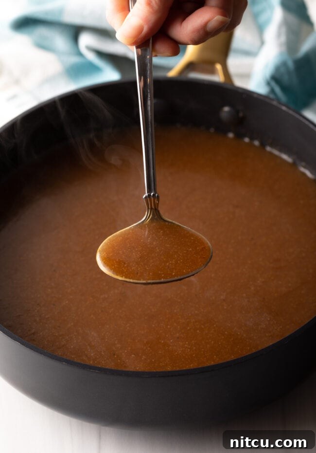 A metal ladle filled with rich brown gravy, ready to be served.