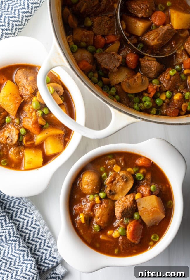 Kitchen Sink Stew 3 Top down Mulligan stew with chopped potatoes, carrots, peas, and chunks of beef in two white bowls.