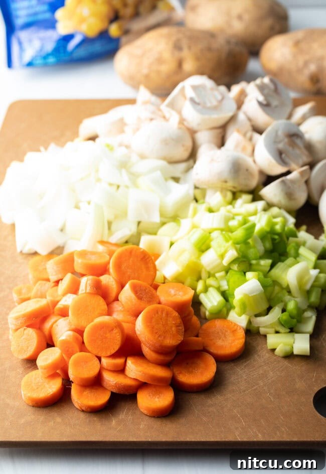 Kitchen Sink Stew 4 Recipe ingredients: Cutting board with chopped carrots, celery, onion, and mushrooms.