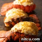 Boiling or Baking Lobster Tails Uncover the Best Method 15 Three plump cooked lobster tails on a baking sheet.