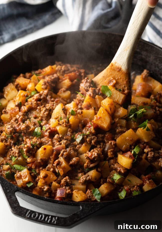 Tuscan Beef & Potato Skillet 8 Wooden spoon stirring in the chopped parsley.