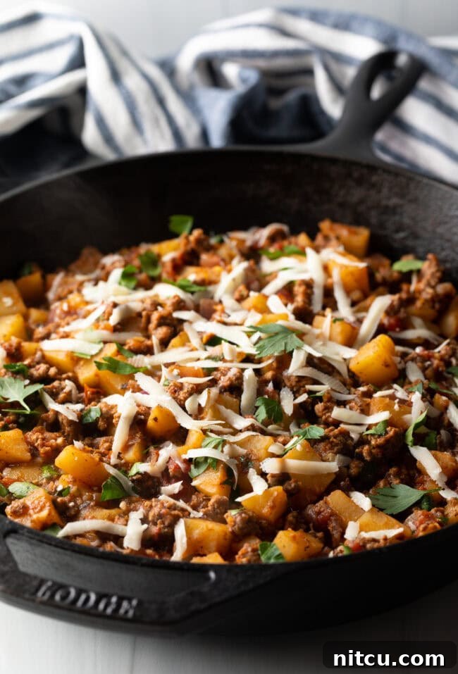 Tuscan Beef & Potato Skillet 9 Ground meat and potatoes, topped with shredded parmesan cheese in a skillet.