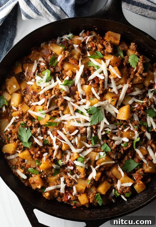 Tuscan Beef & Potato Skillet 10 Top down view ground beef and potatoes, topped with shredded parmesan cheese in a skillet.