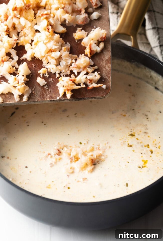 Lobster added to a creamy sauce in a pan. 