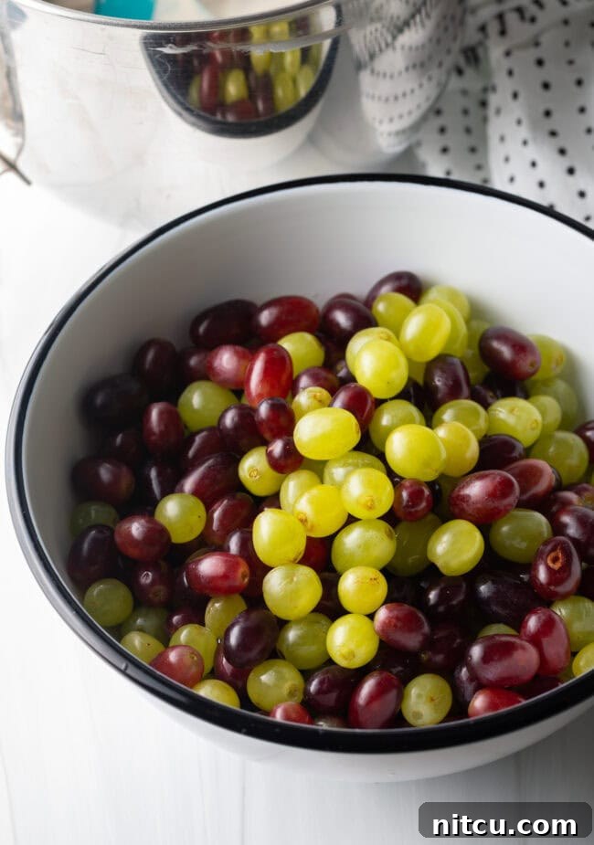 Refreshing Creamy Grape Salad 5 Green and red grapes, removed from the stems, in a white bowl.