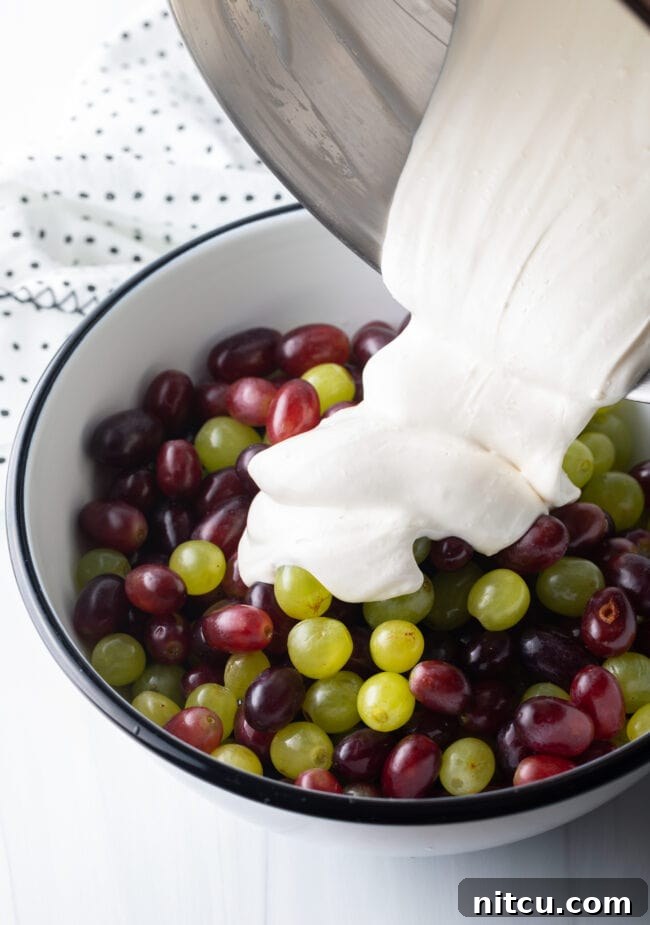 Refreshing Creamy Grape Salad 6 Pouring the cream cheese mixture into the fruit bowl.