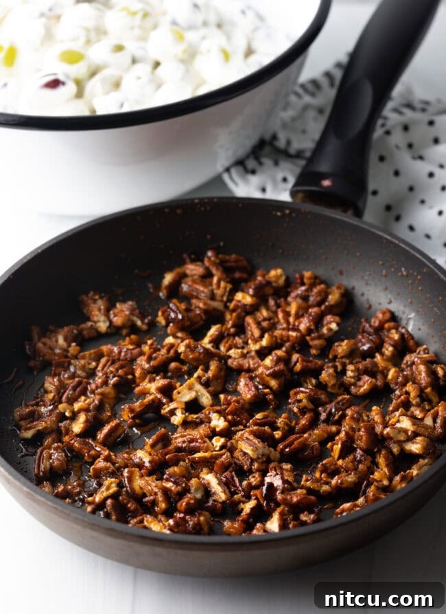 Refreshing Creamy Grape Salad 8 Toasting pecans in a black nonstick skiller.