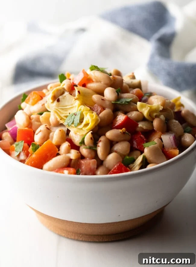 White bowl brimming with white bean and artichoke salad.