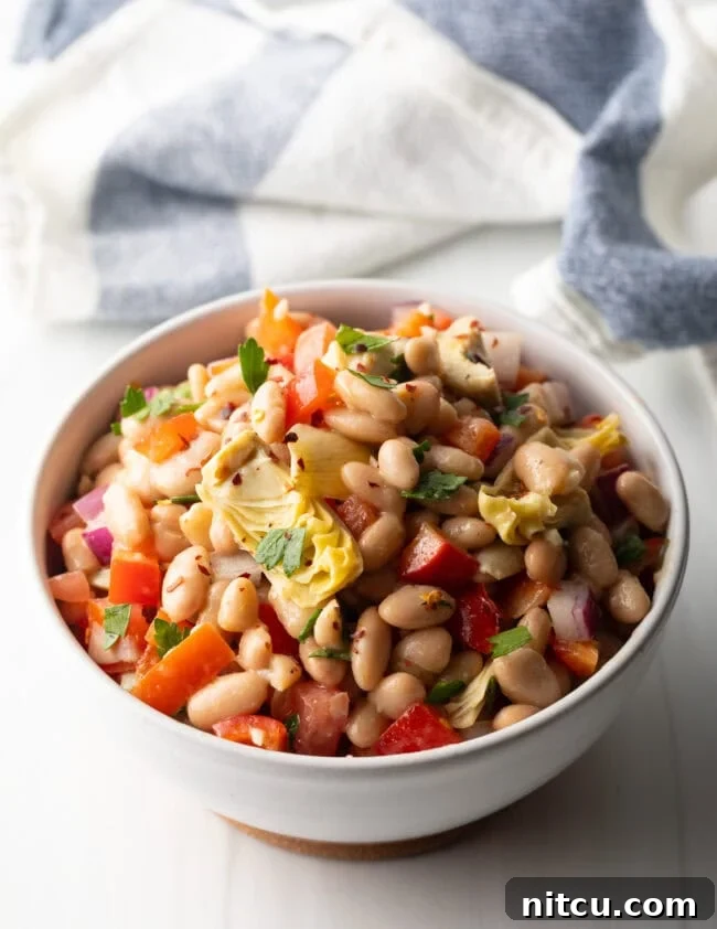White bowl brimming with white bean and artichoke salad.