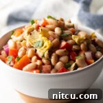 White bowl brimming with white bean and artichoke salad.