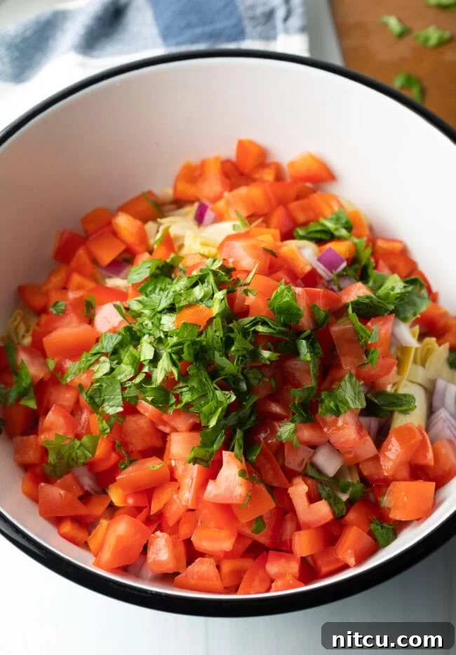Diced tomatoes and fresh herbs in a bowl.