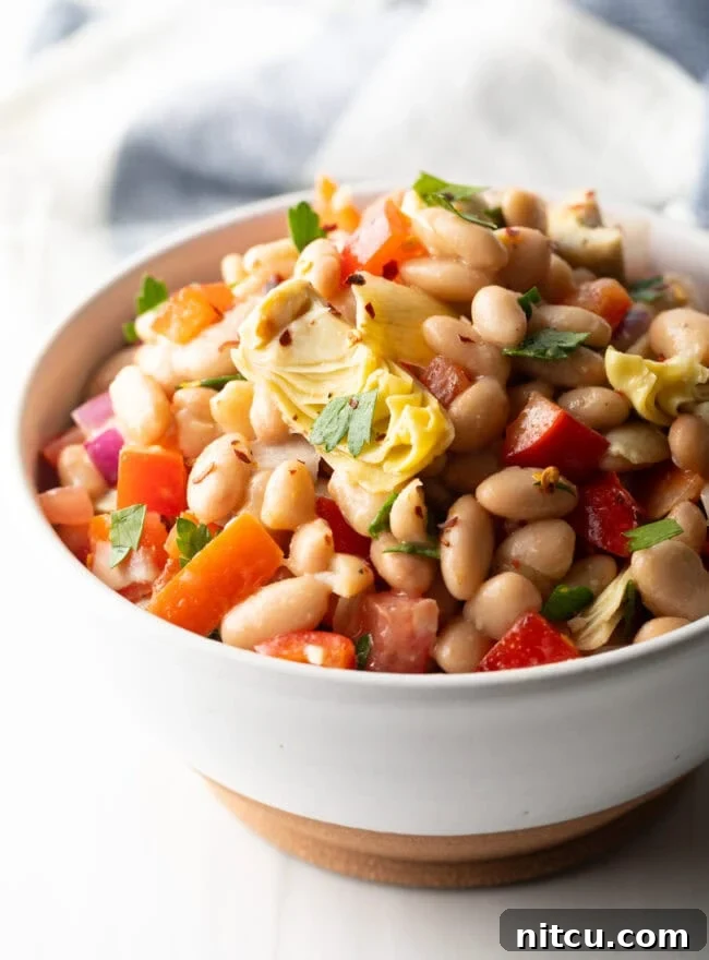 White bowl brimming with white bean and artichoke salad.