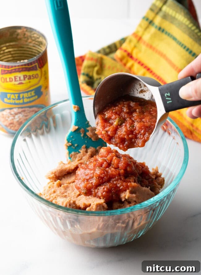 Fiesta Bean Stack 6 Hand with a measuring scoop adding salsa to a glass bowl.